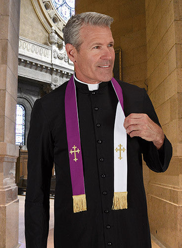 A person wearing a black priest stole with purple and white embroidered gold crosses, standing in a church with a large stained-glass window behind them.